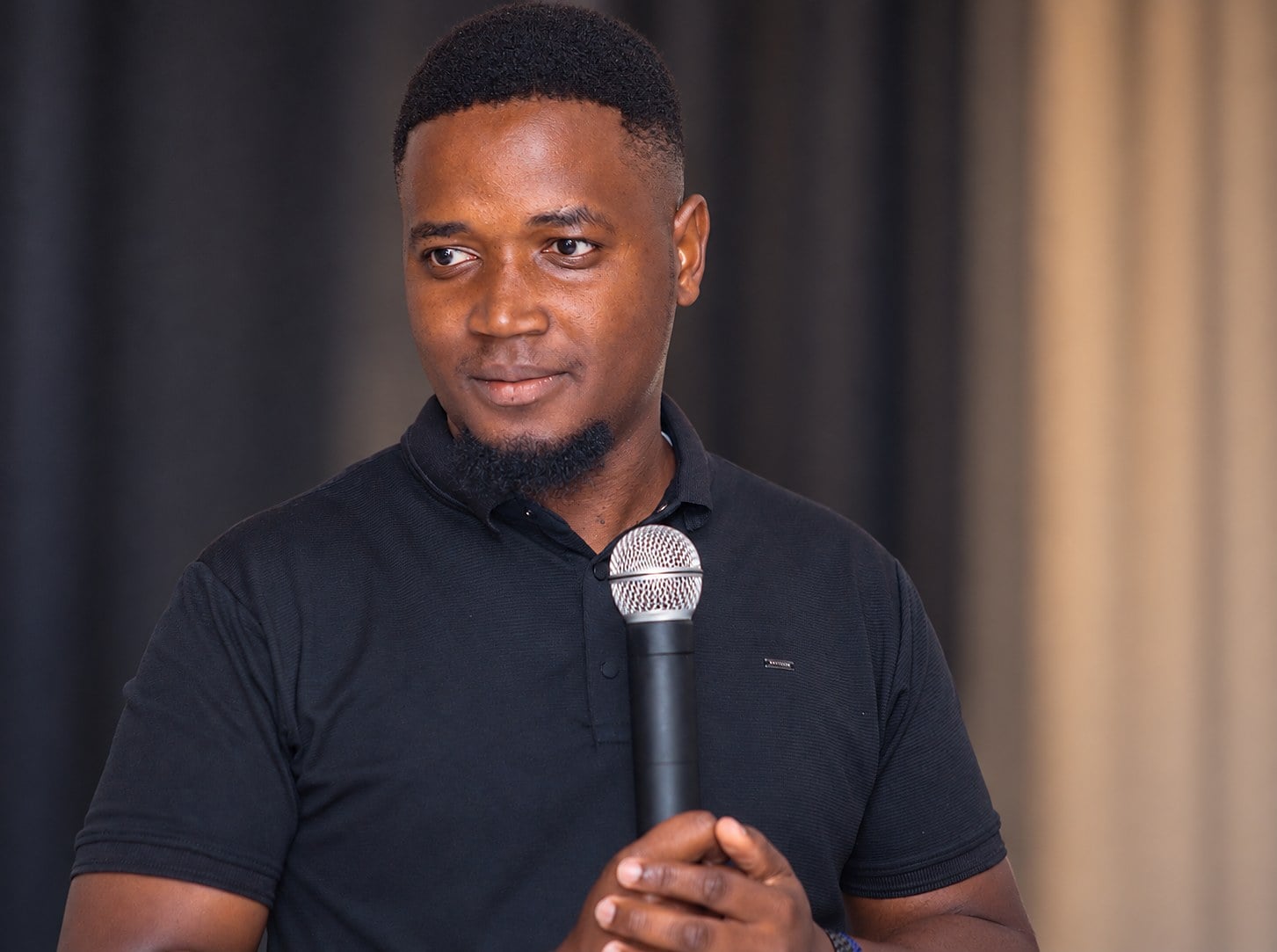 Semu speaking into a microphone on stage